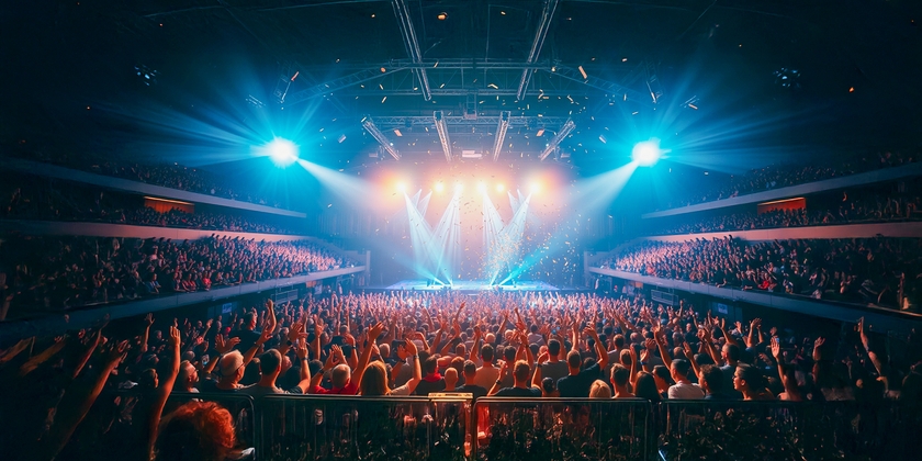 A panoramic view of a concert crowd, showing the GA floor and reserved seating sections.