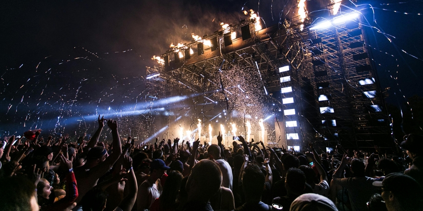 A stage with confetti dropping at night after a big performance from a crowd's point of view