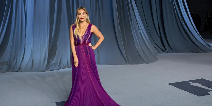 Hilary Duff stands in an elegant eggplant-purple dress.