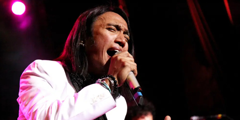 The lead singer of Journey sings into a microphone on stage.