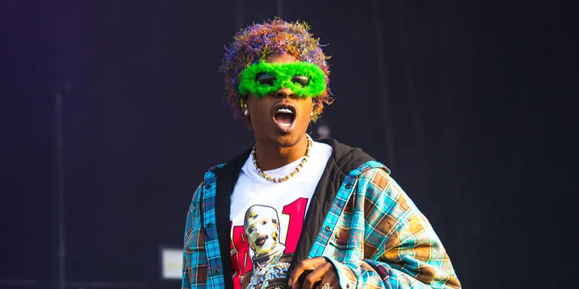 A$AP Rocky makes a face in a green mask on stage.