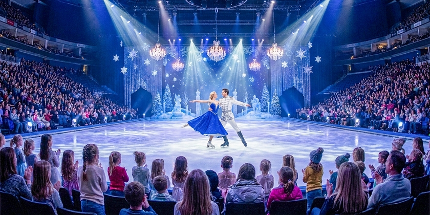 Disney on Ice skaters perform a winter routine for an arena crowd.