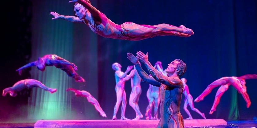 Several acrobats performing a mid-air routine on a colorful stage.