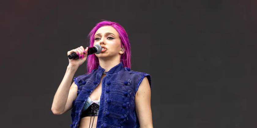 Adela sings on stage with her signature flaming pink hair.