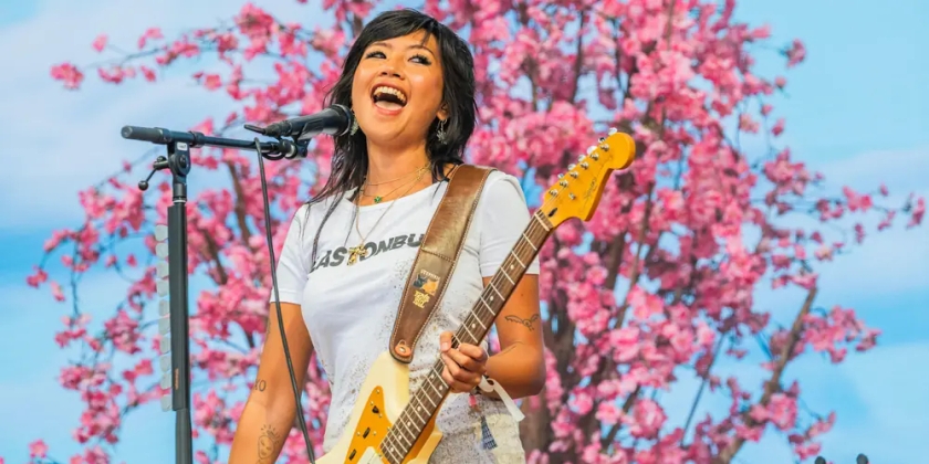 beabadoobee sings on stage in front of a cherry blossom backdrop.
