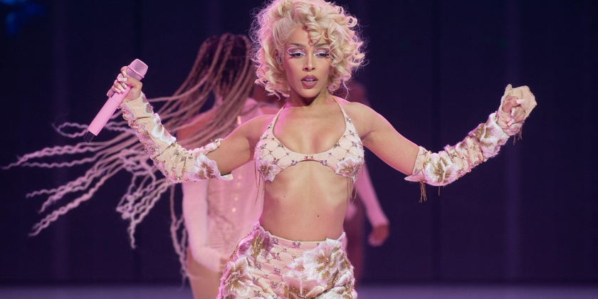 Doja Cat performs on stage with blonde curly hair and backup dancers.