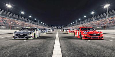 A nighttime view of the Bass Pro Shops Night Race, showing several NASCAR cars lined up.