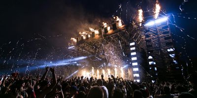 A stage with confetti dropping at night after a big performance from a crowd's point of view