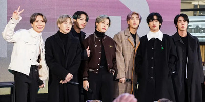 BTS, the K-pop band, stands together. One member throws a peace sign.