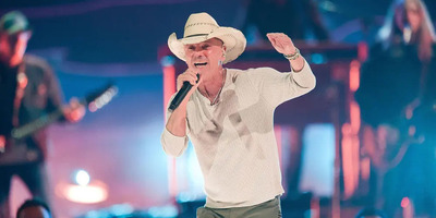 Kenny Chesney sings on stage in a cowboy hat.