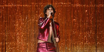Sombr performs on stage wearing a red sparkly suit.