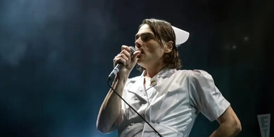 Gerard Way, lead singer of My Chemical Romance, sings into a microphone in a smoky atmosphere.