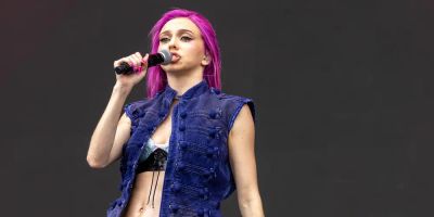 Adela sings on stage with her signature flaming pink hair.