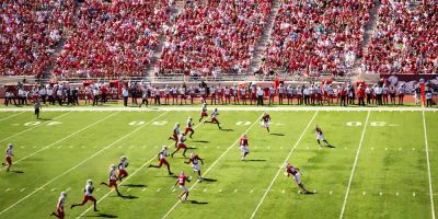 A football team in red jerseys plays in front of a large crowd. 