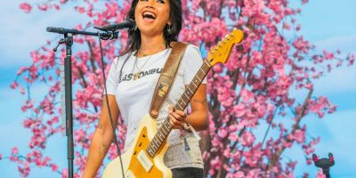 beabadoobee sings on stage in front of a cherry blossom backdrop.